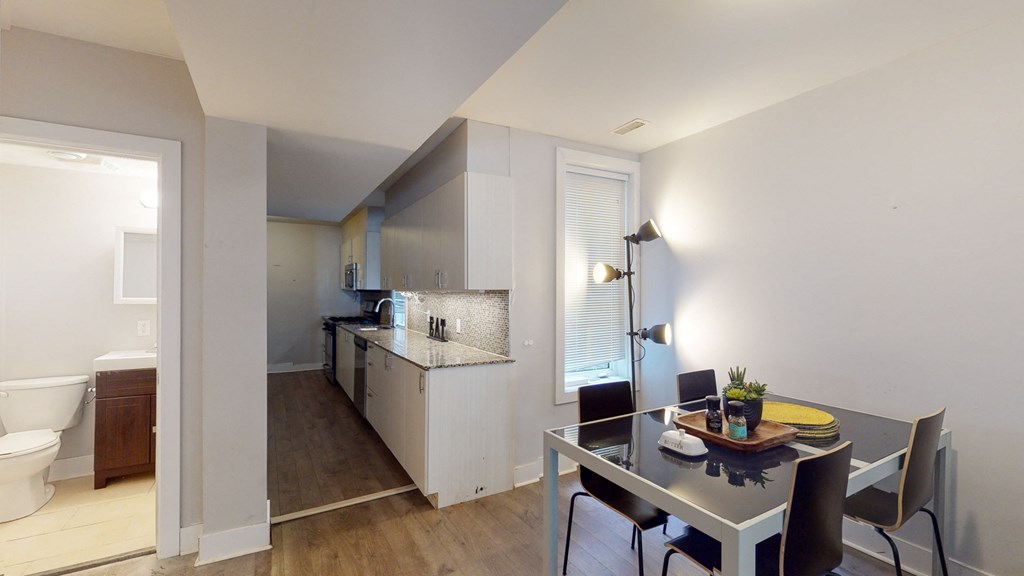a dining room with a table and chairs and a kitchen with a sink