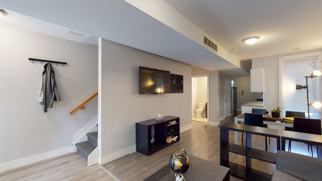 a living room with a tv and a dining room and a staircase