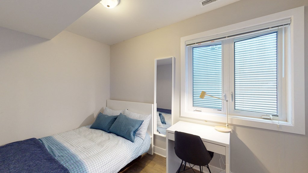 a bedroom with a bed and a desk and a window