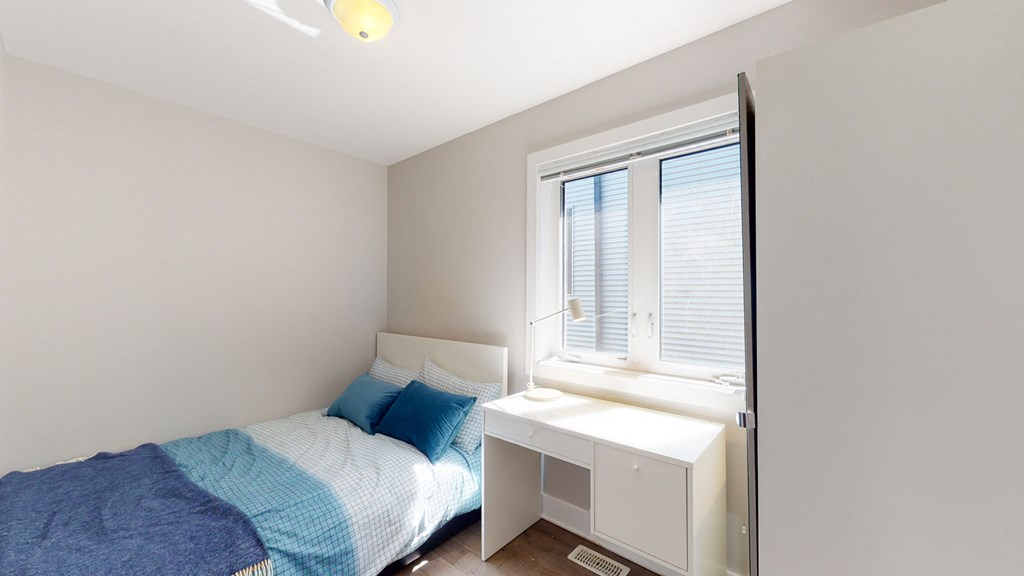 a bedroom with a bed and a desk and a window