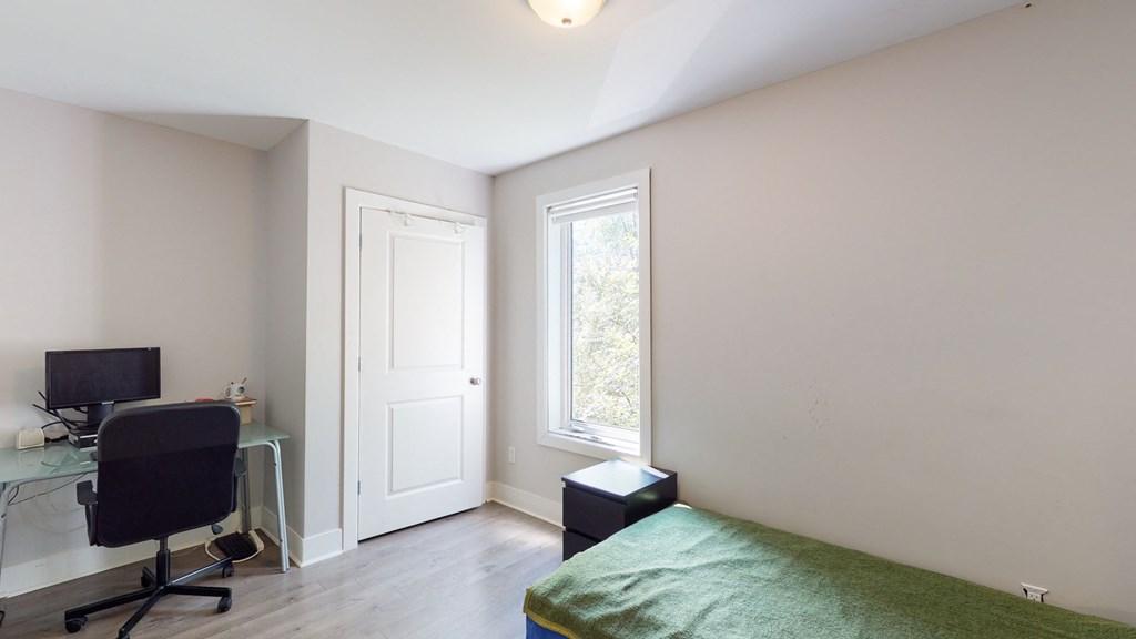 a bedroom with a bed and a desk and a window