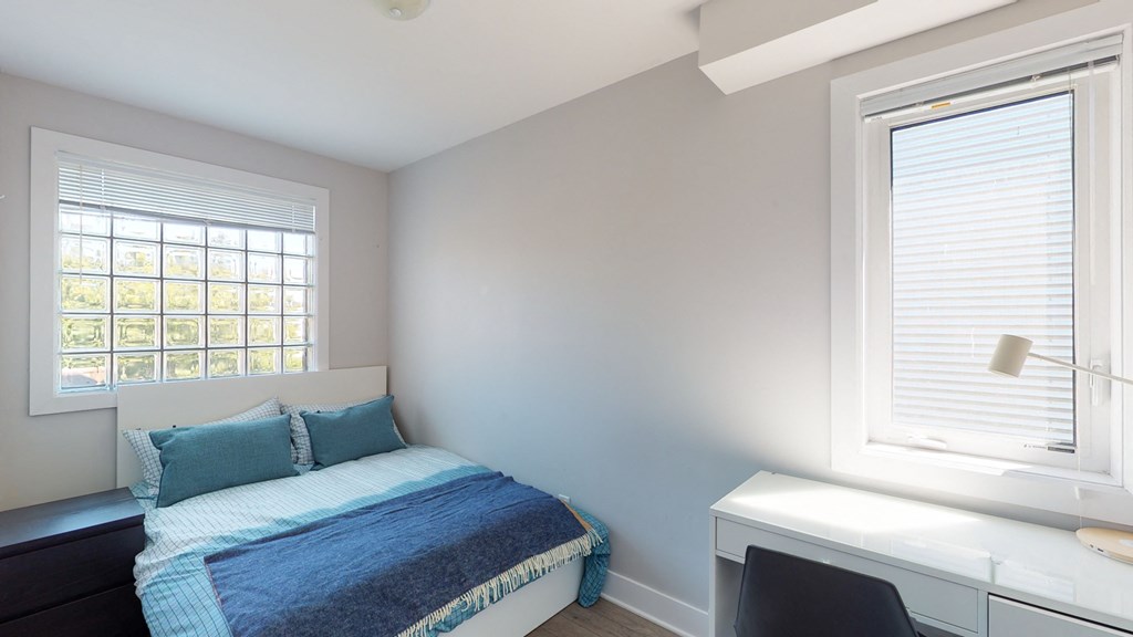 a bedroom with a bed and a desk and a window