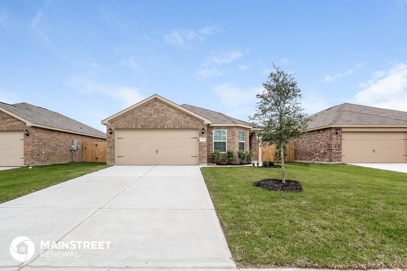 a street view of a brick house with a yard and a sidewalk