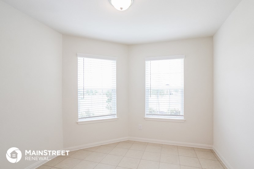an empty room with two windows and a tiled floor
