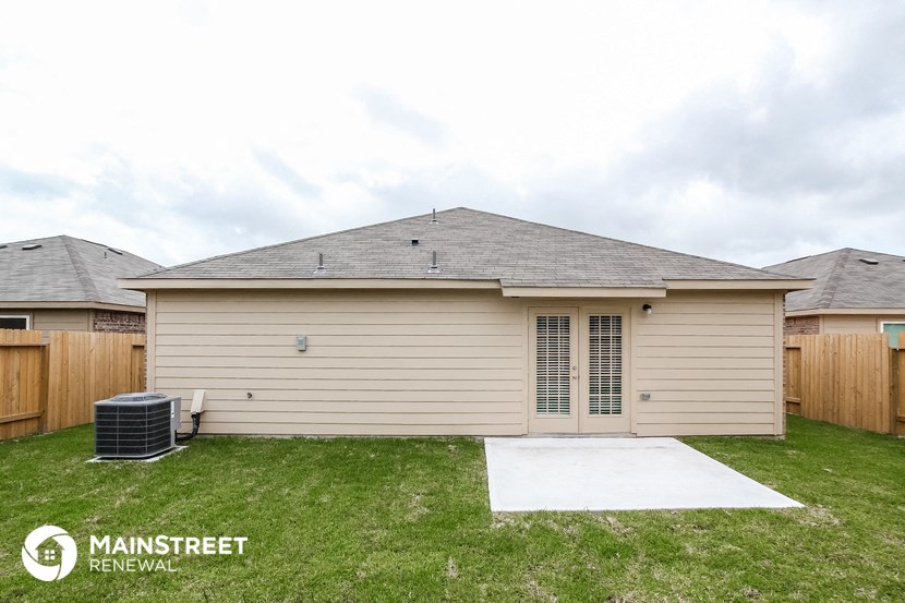 the exterior of a tan house with a driveway and grass