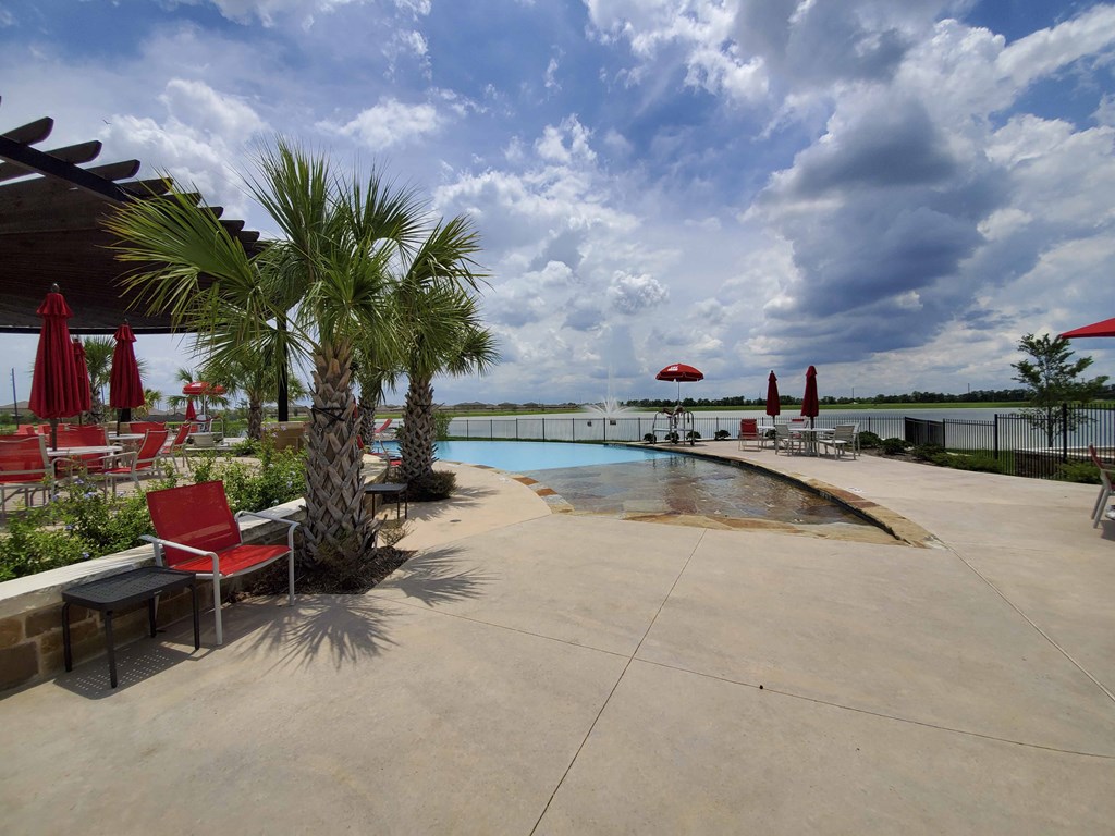 a swimming pool with palm trees and chairs near the water