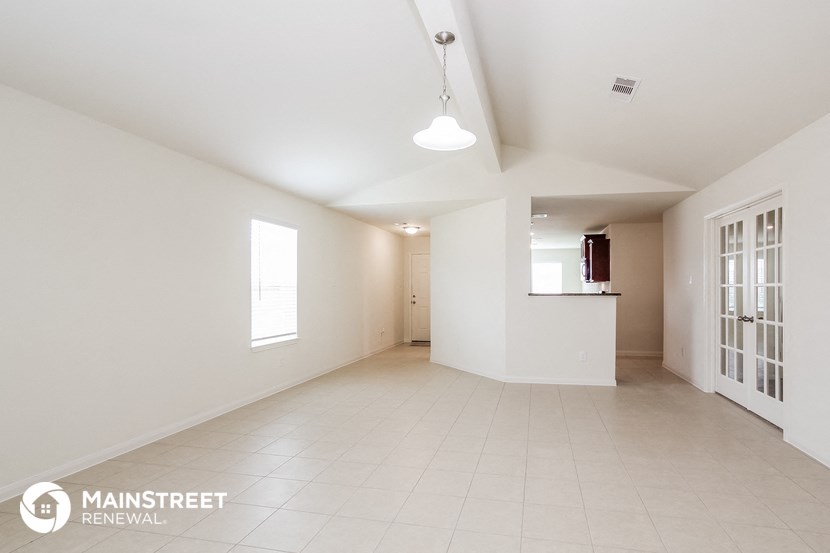 an empty living room and kitchen with white walls and tile flooring