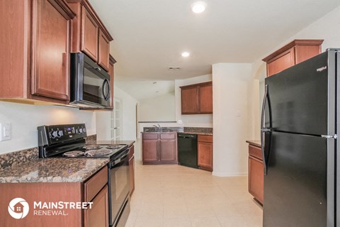 a kitchen with wood cabinets and black appliances and a black refrigerator