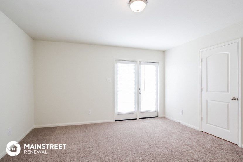 the spacious living room with two doors to the balcony