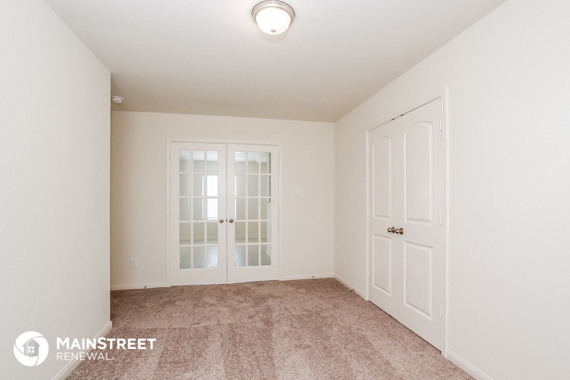 a bedroom with white doors and carpeting and a door to a closet