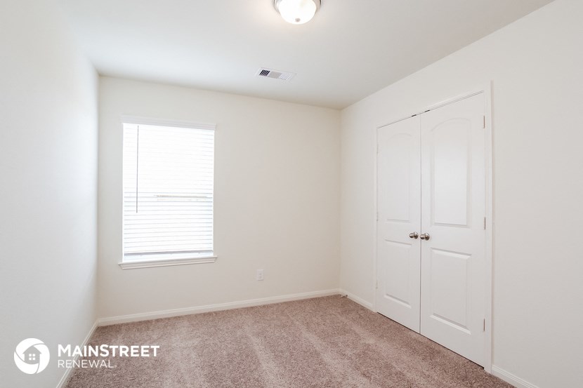 a bedroom with white walls and a white door and a window