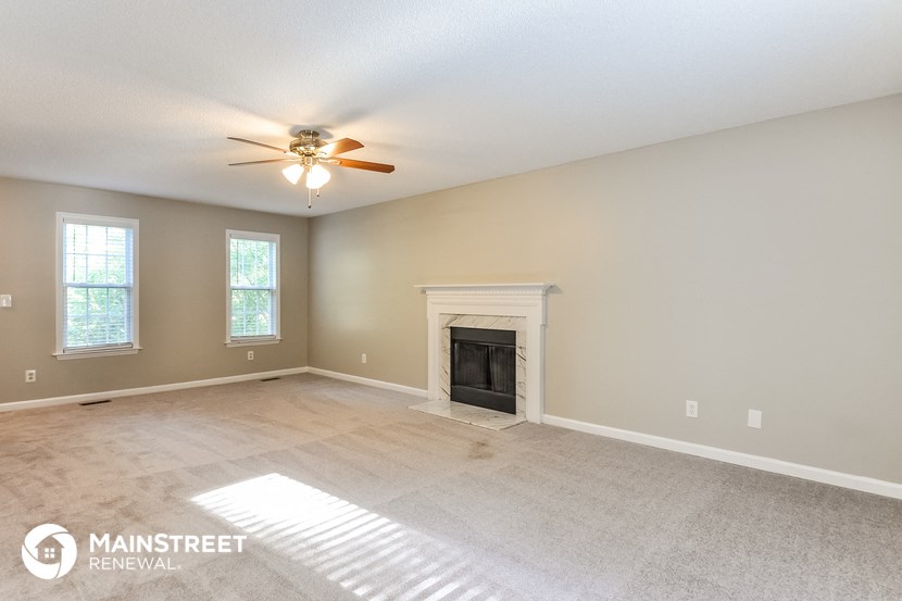 the living room with fireplace and ceiling fan