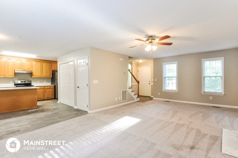 the living room and kitchen of an empty house with a ceiling fan