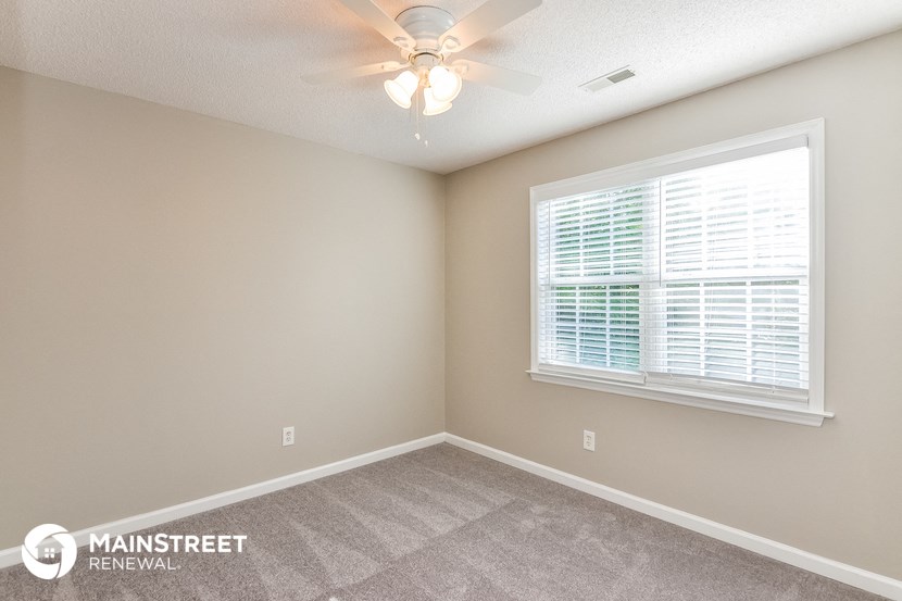 the spacious bedroom has a ceiling fan and a large window
