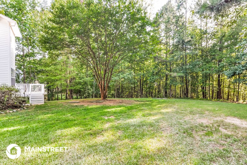 a backyard with trees and a white house