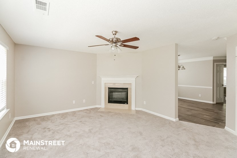 the spacious living room with fireplace and ceiling fan