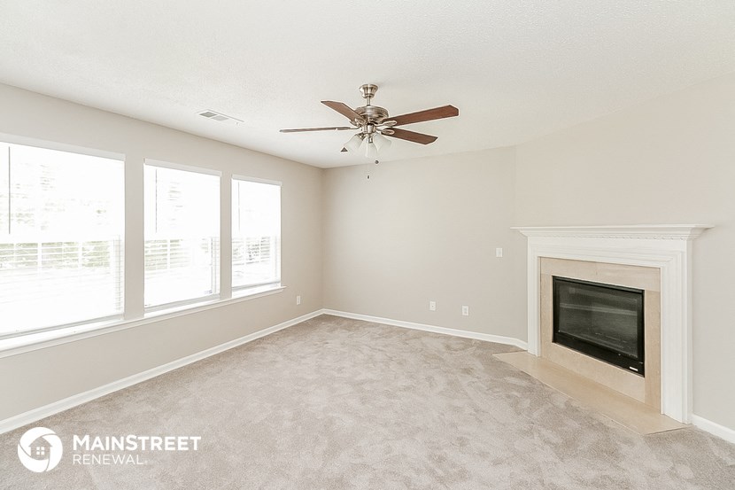 a living room with a ceiling fan and a fireplace