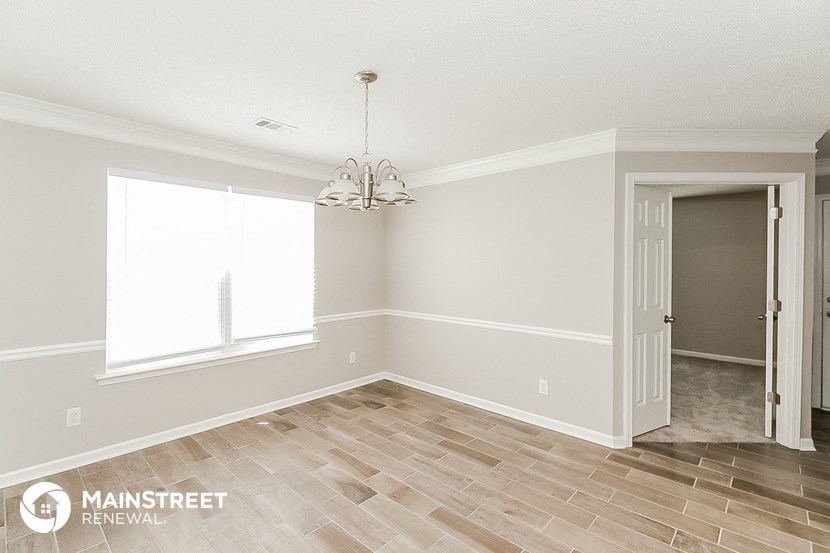the spacious dining room after remodeling with wood flooring and a chandelier