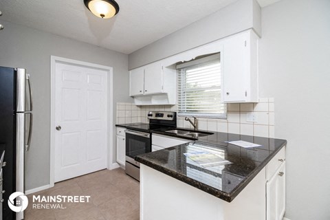 an updated kitchen with black counter tops and white cabinets