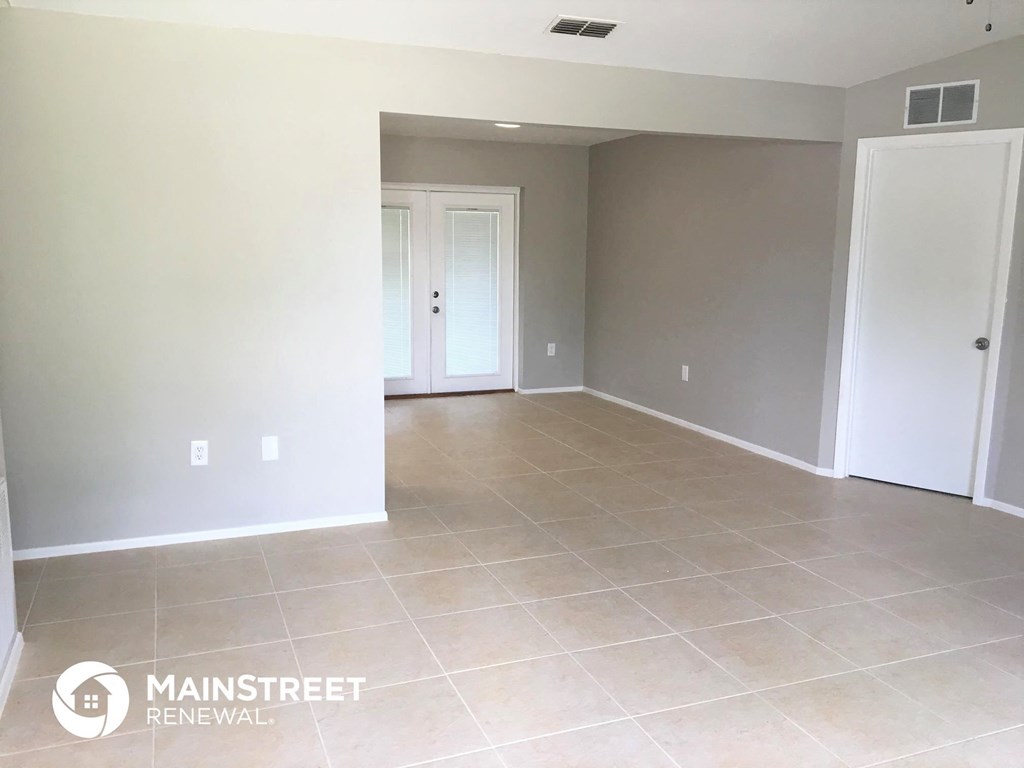 an empty living room with tile flooring and white doors