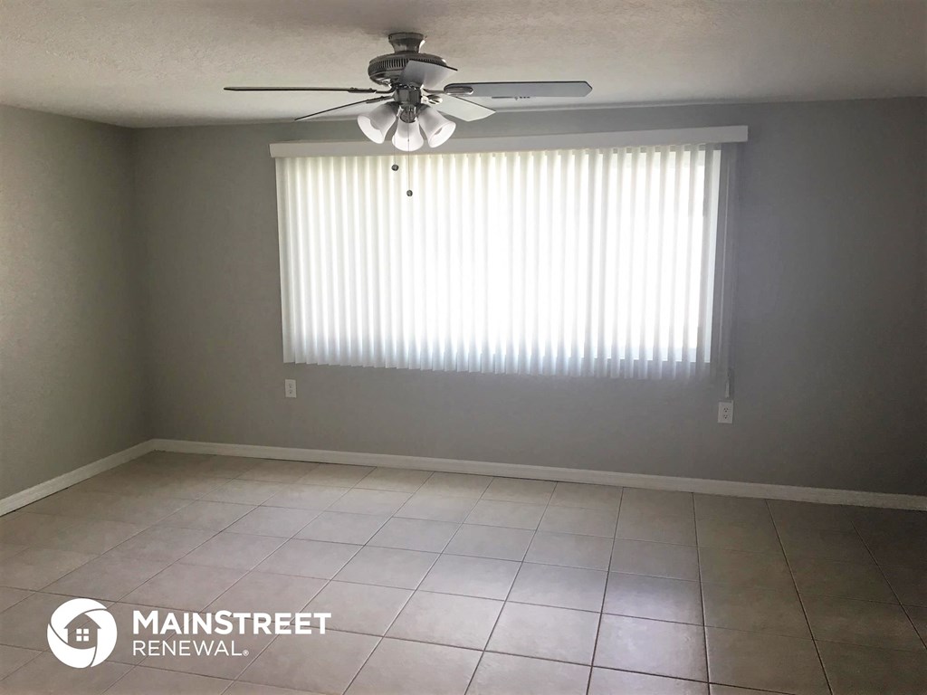 an empty living room with a ceiling fan and a window