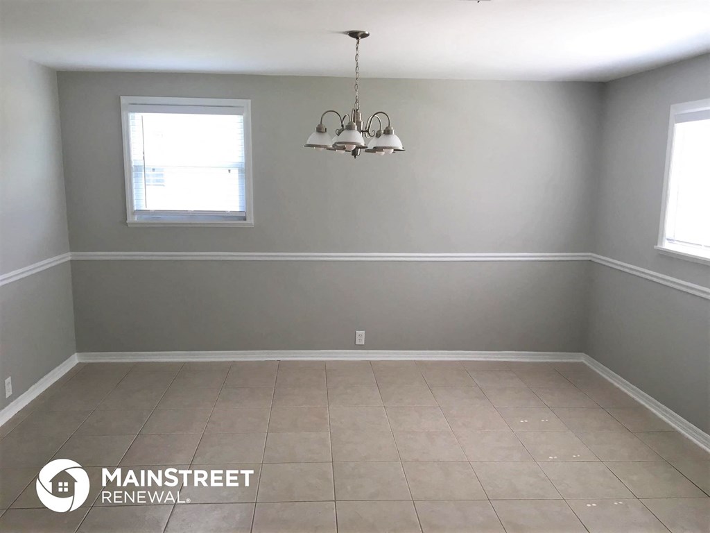 an empty room with a chandelier and two windows