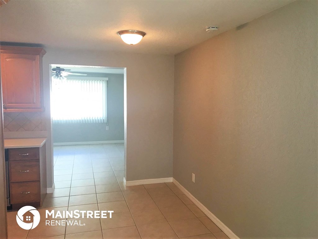 an empty living room with a tile floor and a window