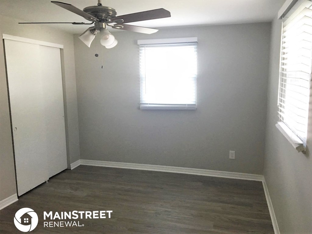 an empty room with a ceiling fan and a window