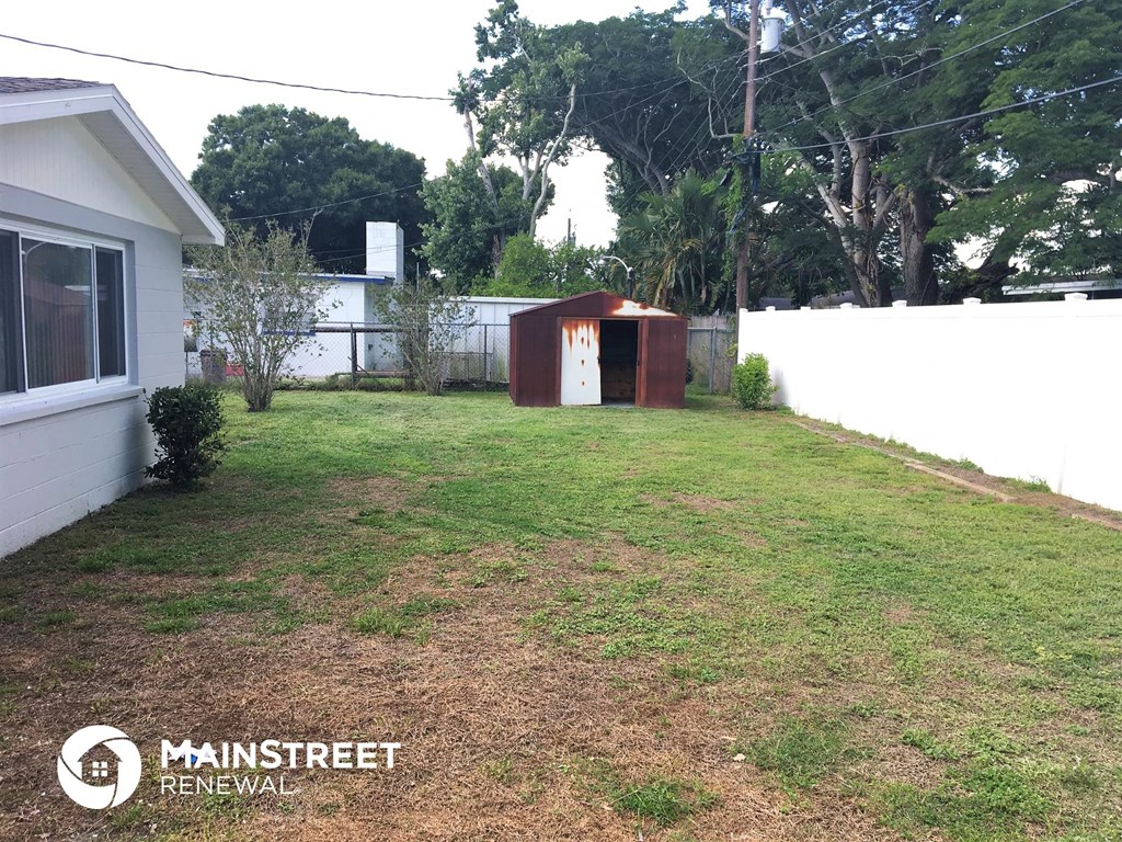 the backyard of a house with a yard and a small shed