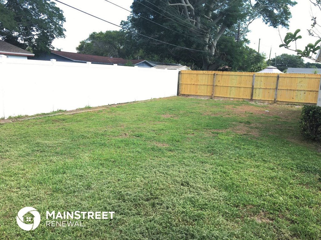 the backyard of a house with a wooden fence and grass