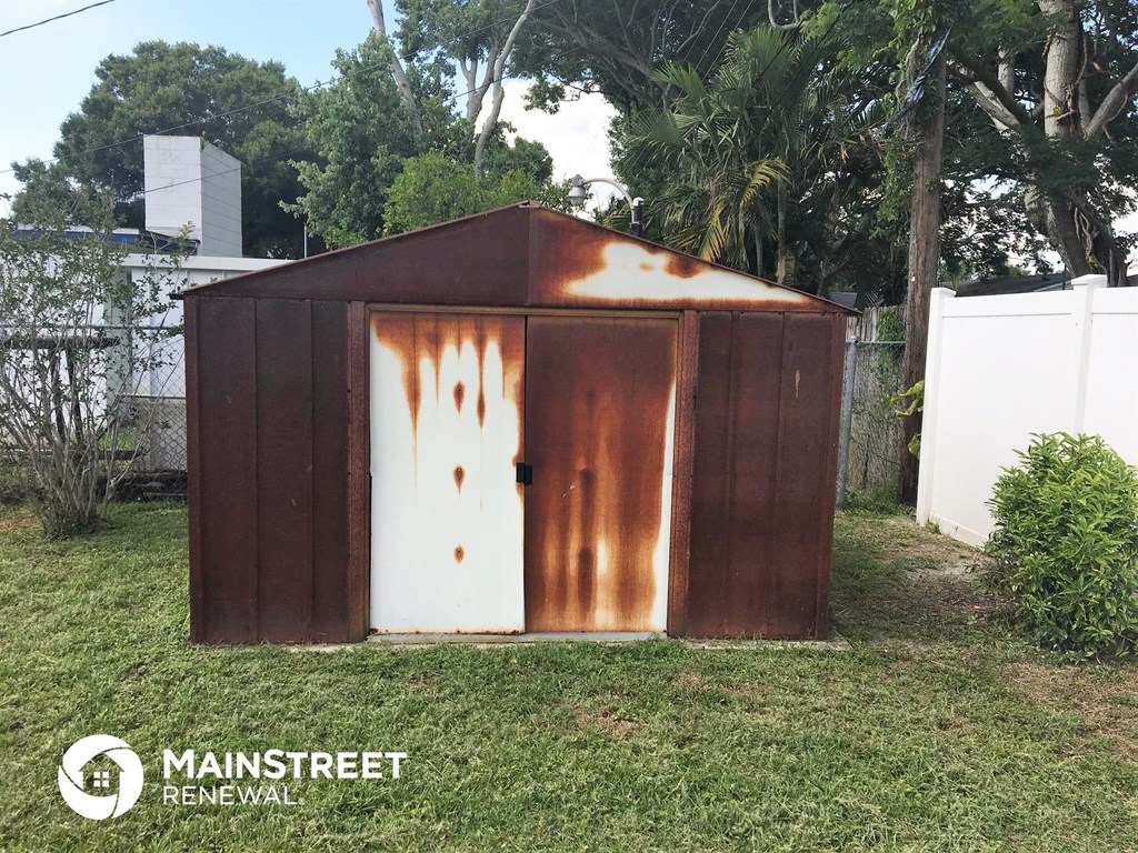 a small wooden shed with a white door in a yard