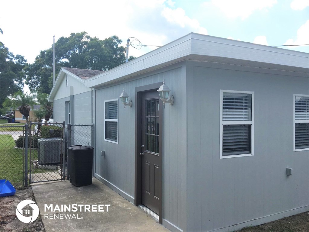 the front of a small house with a door and a gate