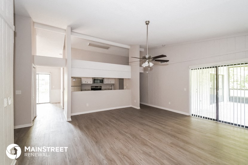 an empty living room with wood flooring and a ceiling fan