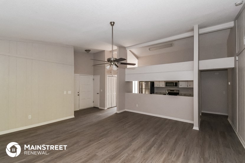 an empty living room and kitchen with a ceiling fan