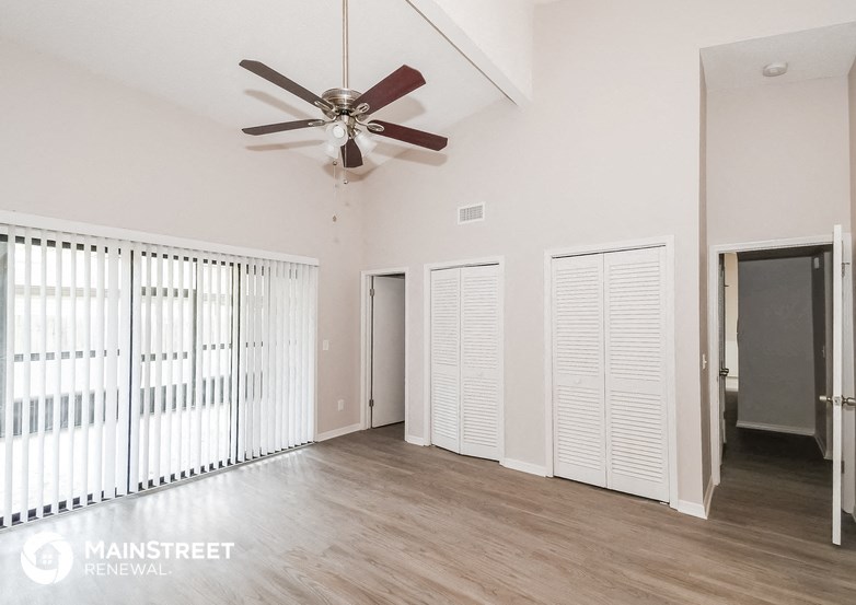 a living room with a ceiling fan and a door to a closet