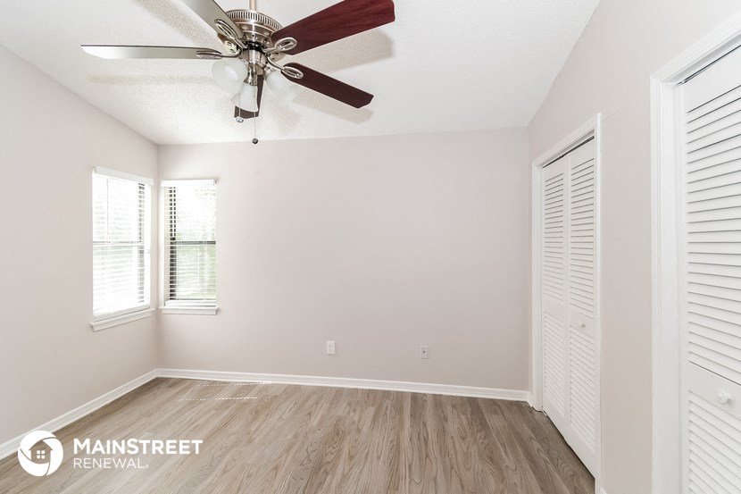 the spacious living room with a ceiling fan and wood flooring