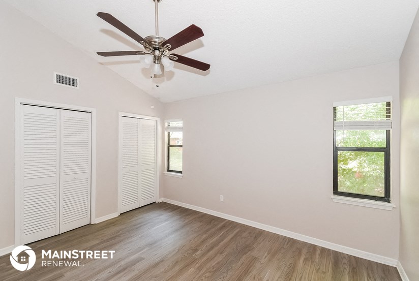 the spacious living room with ceiling fan and wood flooring