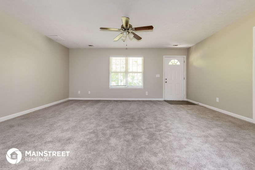 the spacious living room with carpeting and a ceiling fan