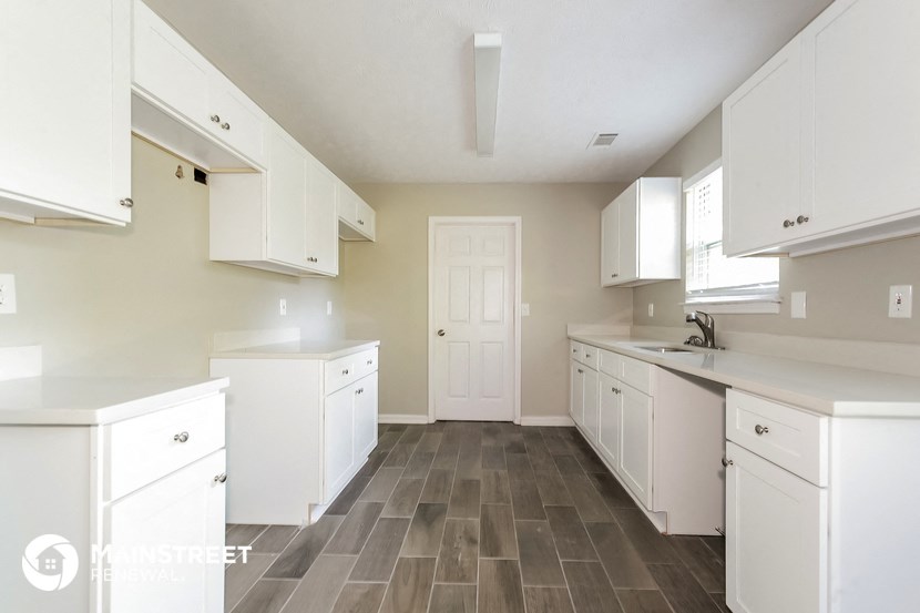 a large white kitchen with white cabinets and a white door