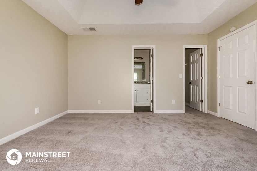 an empty living room with carpet and a door to a bathroom