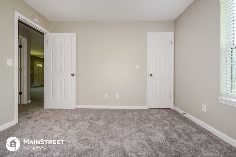 a bedroom with two doors and a carpeted floor