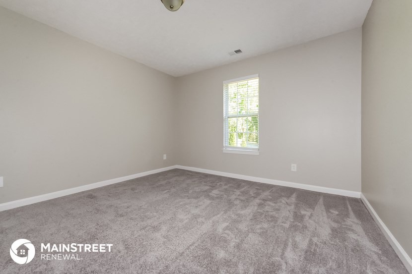 the spacious living room with carpeting and a window
