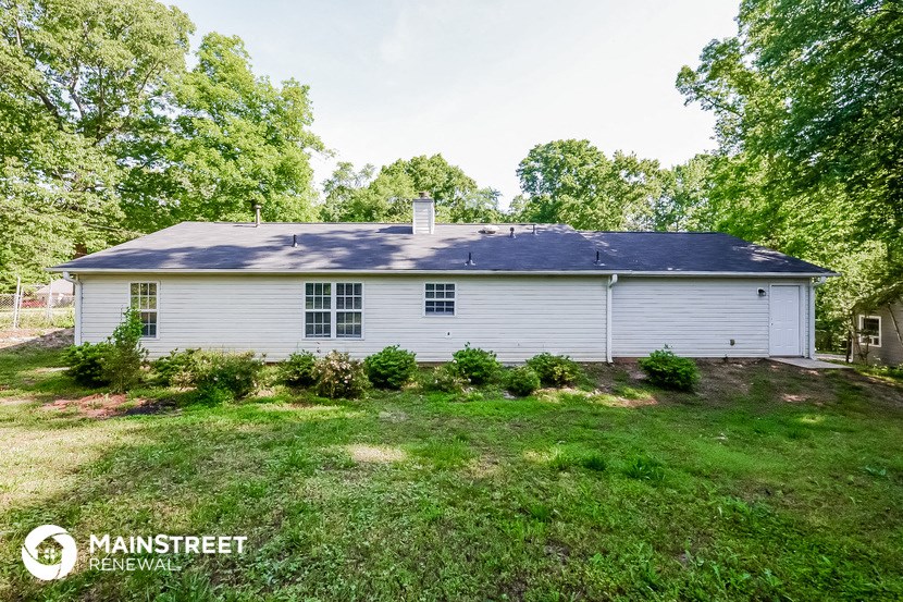 the front of a white house with a lawn and trees