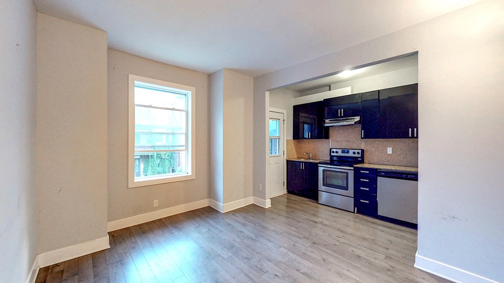 an empty kitchen with wood floors and a window