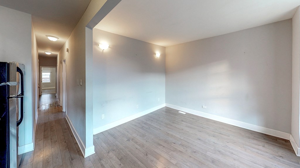 an empty living room with wood floors and white walls