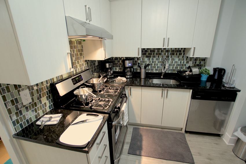 a kitchen with white cabinets and black counter tops and a stove