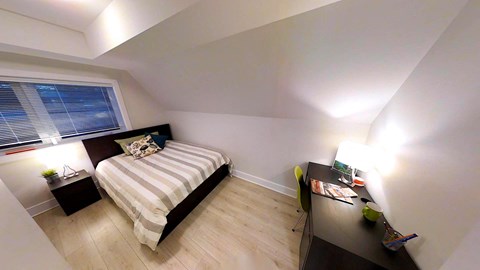 a bedroom with a bed and a desk and a window