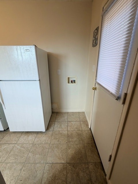 A white refrigerator in a kitchen with a tiled floor.