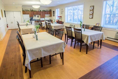 a dining room with tables and chairs and a kitchen