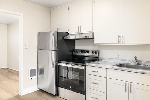 a kitchen with white cabinets and stainless steel appliances and a refrigerator